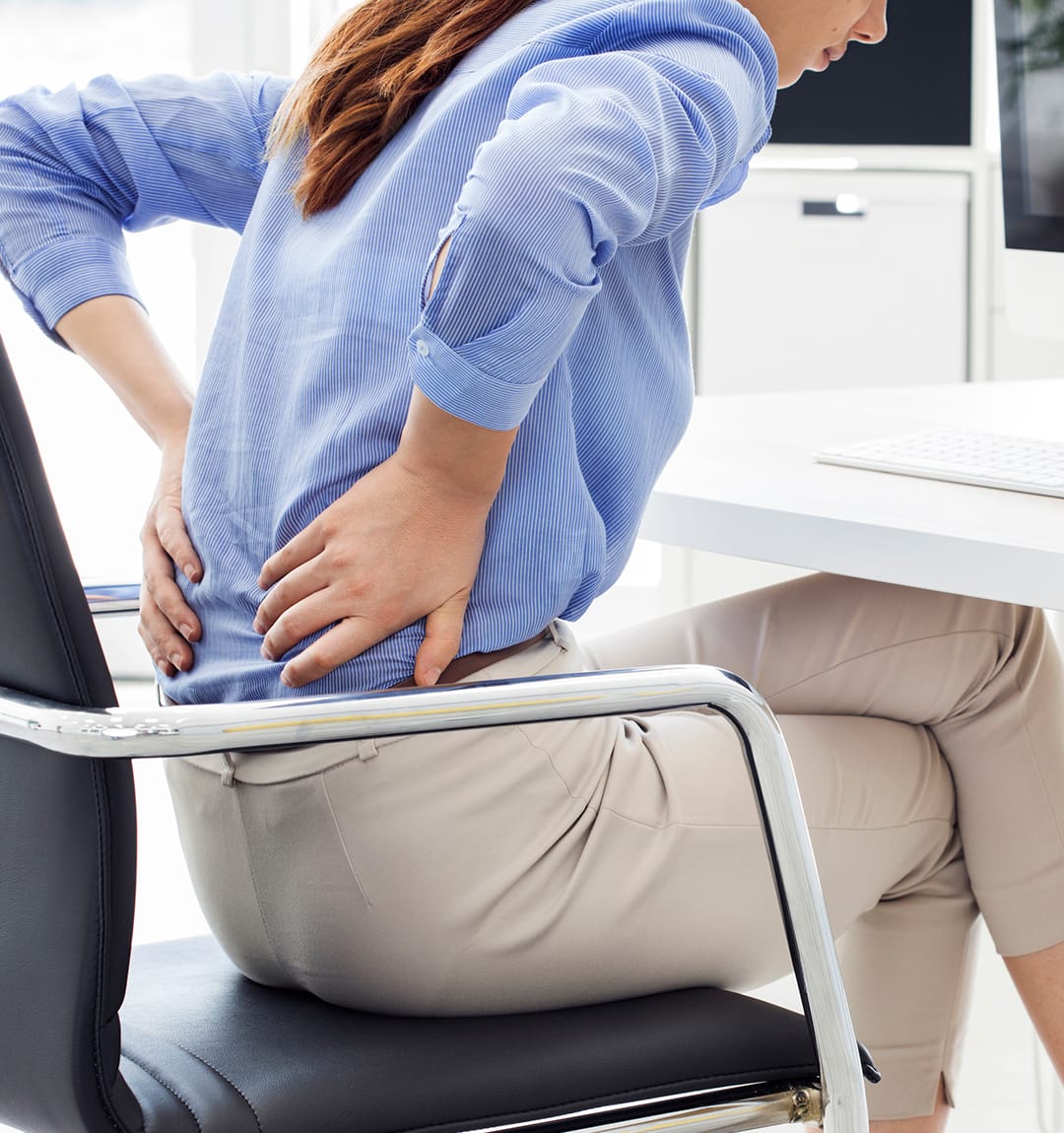 Woman at a desk holding her lower back